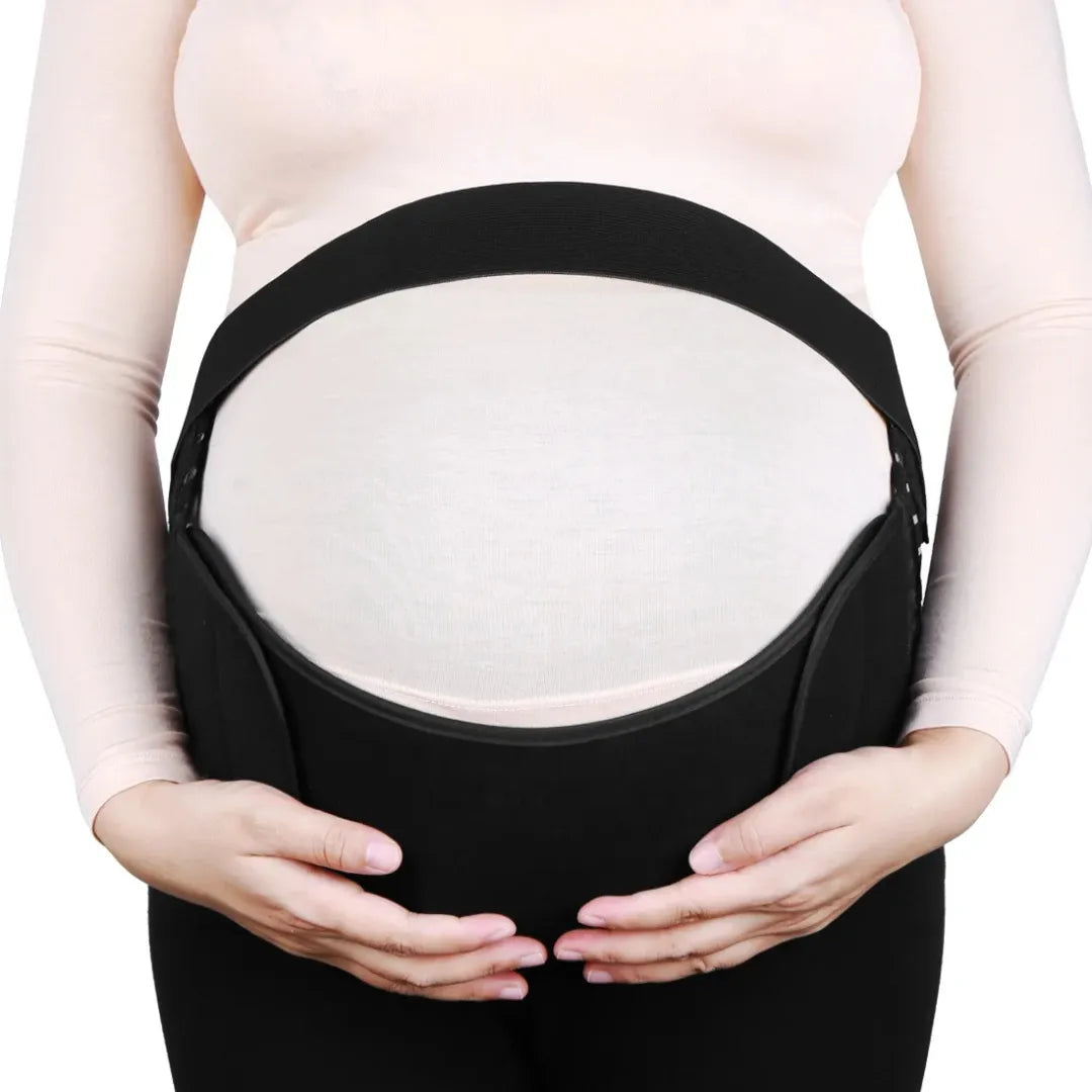 Front view of a pregnant woman's belly supported by a black maternity belly band, with hands cradling the bum.
